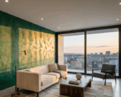 Moderná obývacia izba s panoramatickým výhľadom na mesto a výraznou smaragdovo zelenou akcentovou stenou s textúrou benátskeho štuku.